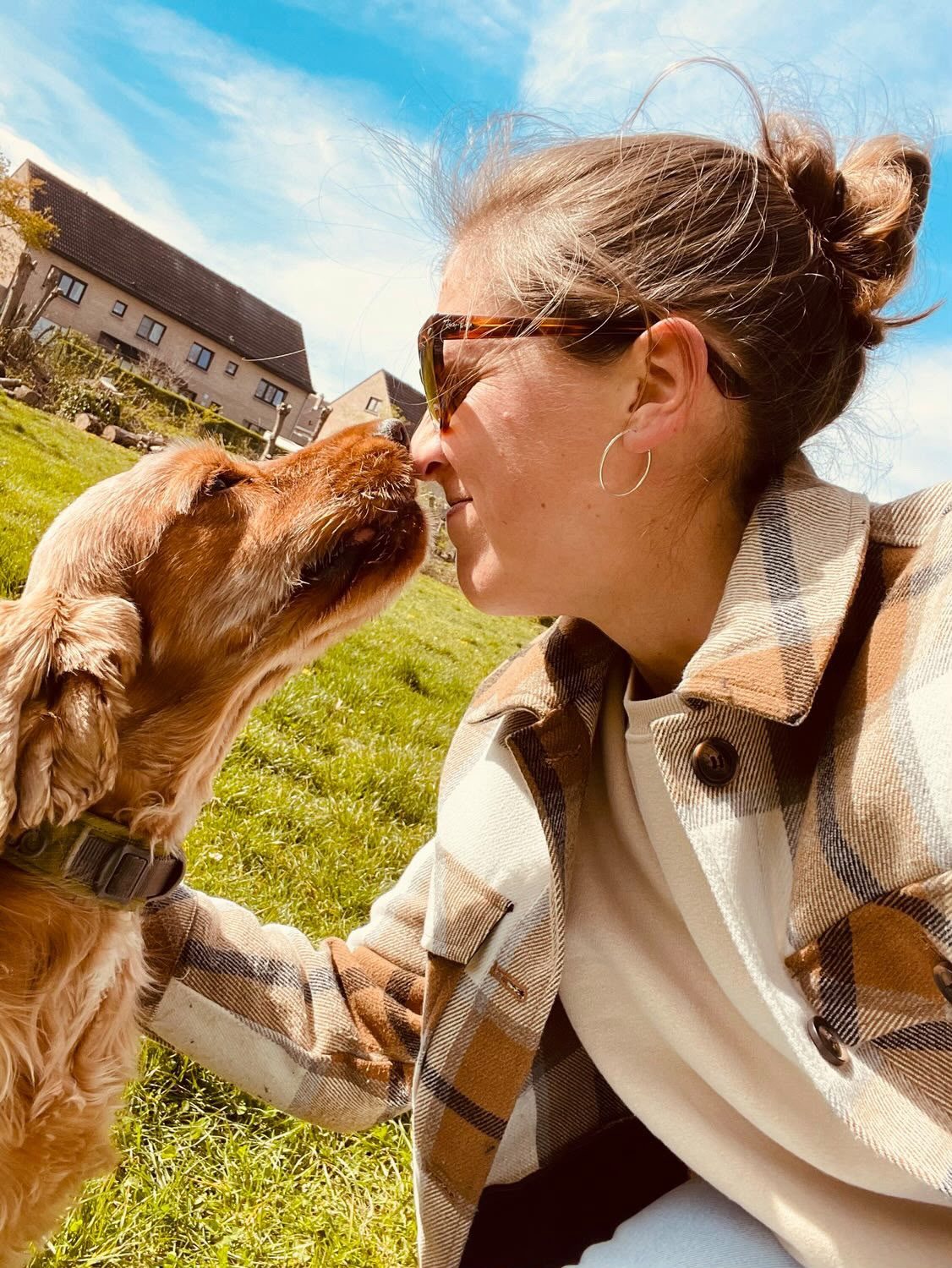 Vrouw en hond, neus aan neus in het gras